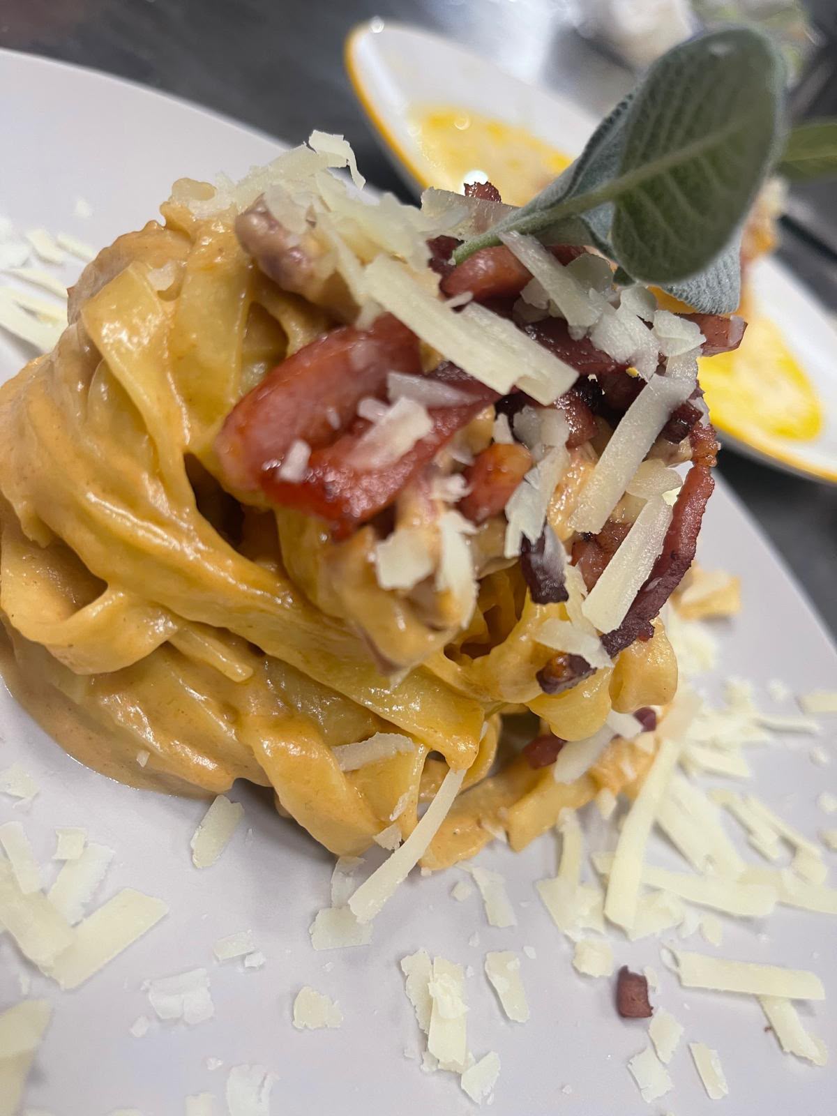 Tagliatelle con crema di melanzane, speck croccante e scaglie di Parmigiano